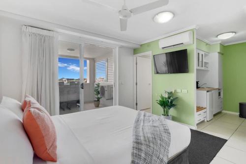 a bedroom with a white bed and a flat screen tv at Peak Studio - Highview Haven across Shopping Centre in Cairns