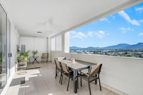 a dining room with a table and chairs and a large window at Cairns City Escape - Elevated Modern Haven with Pool in Cairns