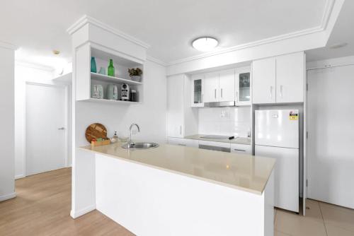 a white kitchen with a sink and a refrigerator at McLeod Rise - Cairn Base with Rooftop Pool & Spa in Cairns