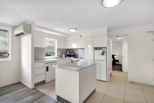 a large white kitchen with white cabinets and appliances at Cairns Central Adjacent Suites, Steps to Esplanade in Cairns