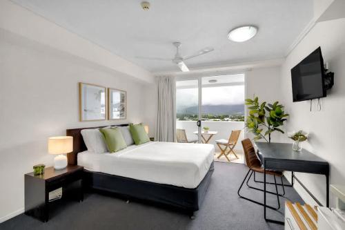 a bedroom with a bed and a desk and a television at Cairns Central Adjacent Suites, Steps to Esplanade in Cairns