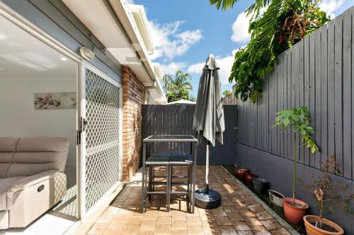 a small patio with a chair and an umbrella at Tropical Cove at Trinity Beach with Lagoon Pool in Trinity Beach