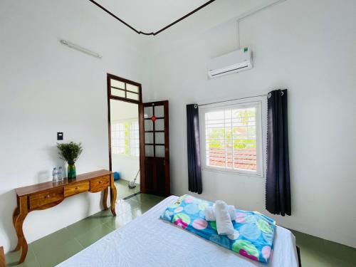 a bedroom with a bed and a desk and a window at Katie's homestay in Ðông Mỹ (2)