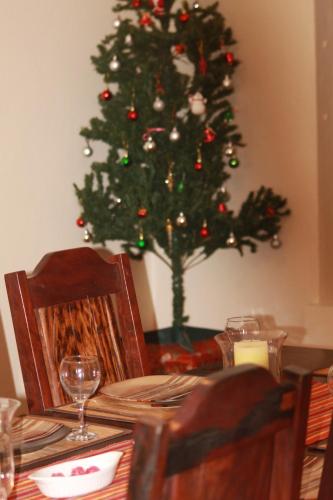 a dining room table with a christmas tree in the background at Grysbok Self Catering Accommodation in Oudtshoorn