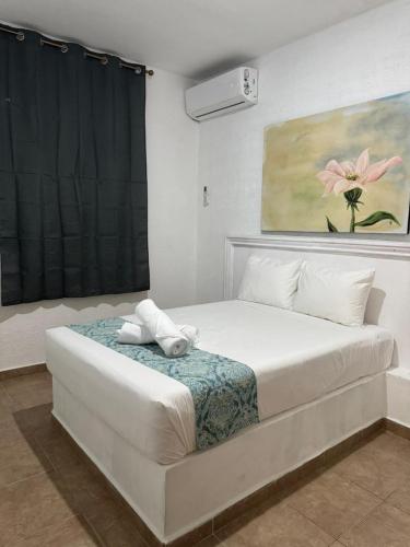 a white bed in a room with a painting at Casa Dixam Luum in Puerto Morelos