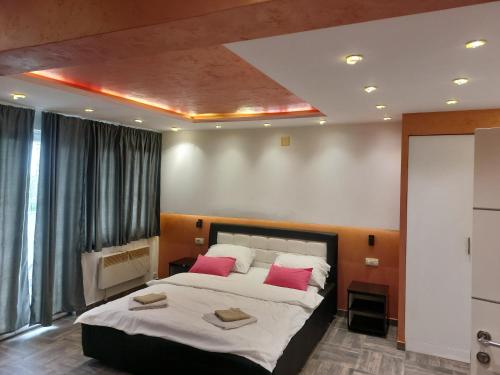 a bedroom with a large bed with two pink pillows at De Lux Apartment Maki in Banja Luka