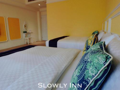 two beds in a room with yellow walls at Slowly inn in Hengchun