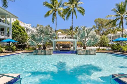 a large swimming pool with palm trees in a resort at Couple's Coastal Haven Retreat at The Beach Club in Palm Cove