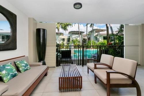 a living room with a couch and chairs and a pool at Poolside Bliss: A Modern Resort Sanctuary in Port Douglas