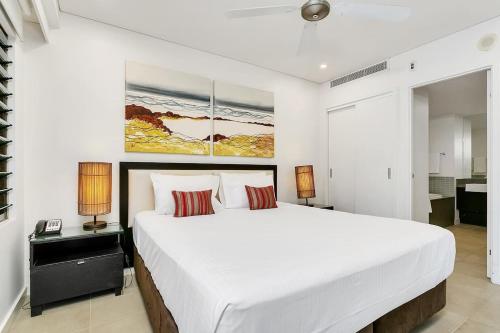 a white bedroom with a large bed and two lamps at Poolside Bliss: A Modern Resort Sanctuary in Port Douglas