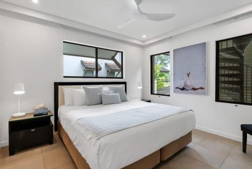 a bedroom with a large bed and two windows at Rooftop Tranquility at Stunning Temple Resort in Port Douglas