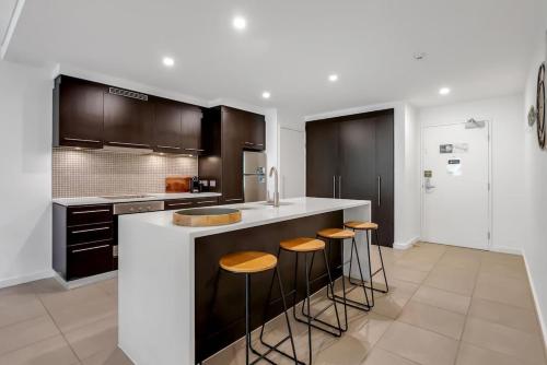 a kitchen with black and white cabinets and bar stools at Rooftop Tranquility at Stunning Temple Resort in Port Douglas
