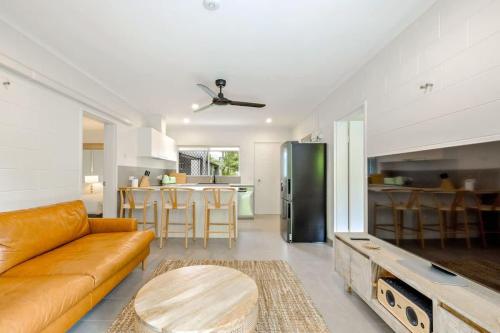 a living room with a couch and a table and a kitchen at The Tropical Trinity - A Breezy Beachside Getaway in Trinity Beach