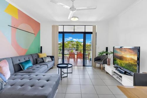 a living room with a couch and a tv at The Loft - Trendy Coastal Charm with Pool in Cairns