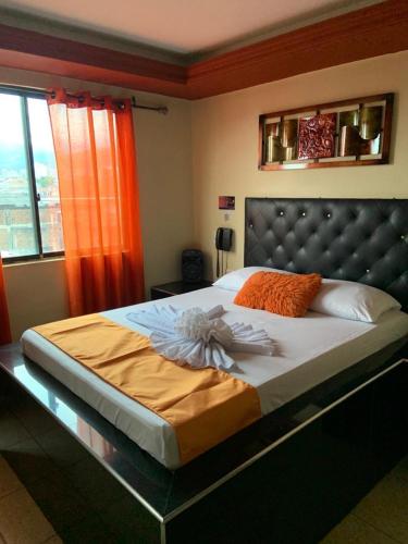 a bedroom with a large bed with an orange curtain at Hotel Rio Sol in Cali