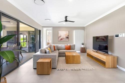 a living room with a couch and a tv at The Elysian at Argentea - Beachside Stay with Pool in Palm Cove