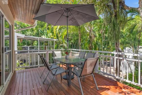 a table and chairs on a deck with an umbrella at Nirvana - Steps to Four Mile Beach with Shared Pool in Port Douglas