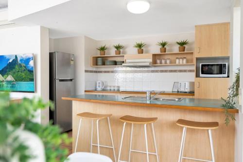 a kitchen with two bar stools and a counter top at Wallaby Beach House - Resort-style Comforts in Trinity Beach