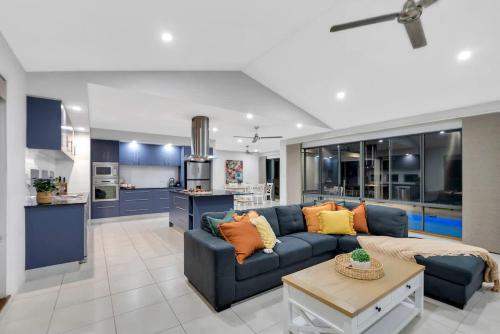 a living room with a blue couch and a kitchen at Trinity Beach Oasis - Poolside Retreat and Serenity in Trinity Beach