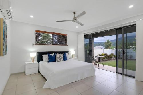 a white bedroom with a bed and a balcony at Trinity Beach Oasis - Poolside Retreat and Serenity in Trinity Beach
