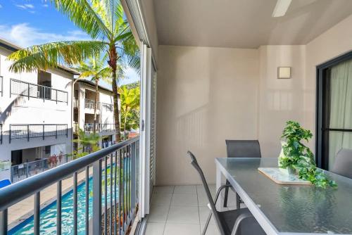 a balcony with a table and chairs and a swimming pool at Lagoon Lookout - Poolside Studio near Trinity Beach in Trinity Beach