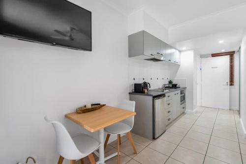 a small kitchen with a wooden table and chairs at Laguna Edge - Swim-Out Studio, near Sea & Dining in Trinity Beach