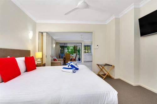 a bedroom with a large white bed with red pillows at Escape for Two - A Boutique Tropical Treasure in Port Douglas
