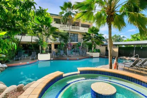 a swimming pool in front of a hotel with palm trees at Escape for Two - A Boutique Tropical Treasure in Port Douglas