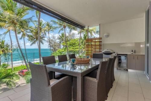 a dining room with a table and chairs and the ocean at Bougainvillea - Beachside Luxury at The Drift in Palm Cove