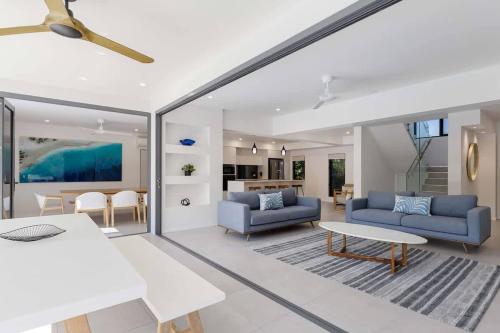 a living room with two blue couches and a table at Raphari At The Cove - A Stunning Poolside Escape in Palm Cove