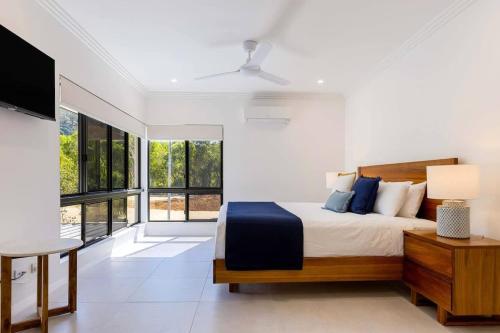 a bedroom with a bed and a large window at Raphari At The Cove - A Stunning Poolside Escape in Palm Cove