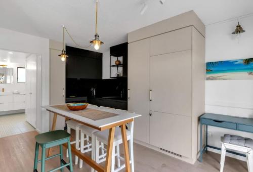 a kitchen with white cabinets and a table and stools at Mira - Poolside Beach Retreat by Four Mile Beach in Port Douglas