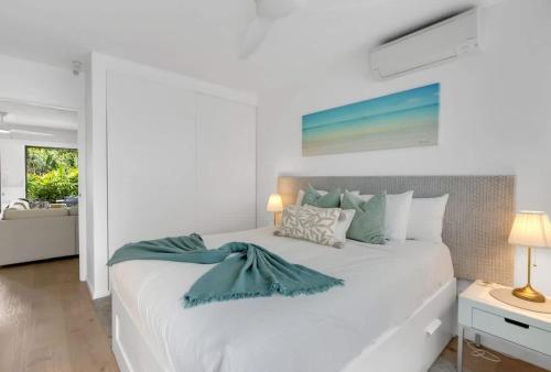 a bedroom with a white bed with a blue blanket on it at Mira - Poolside Beach Retreat by Four Mile Beach in Port Douglas