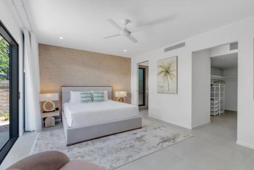 a white bedroom with a bed and a large window at Salt - Beachfront Luxe with Private Pool in Palm Cove