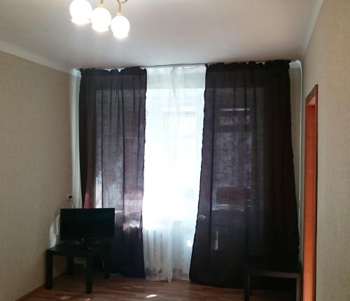 ノヴォシビルスクにあるApartamenty na Karla Marksa 13の窓(黒いカーテン、テレビ付)が備わる客室です。