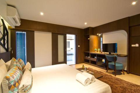 ein Schlafzimmer mit einem Bett und einem Schreibtisch mit Fernseher in der Unterkunft Coco Hotel in Bangkok