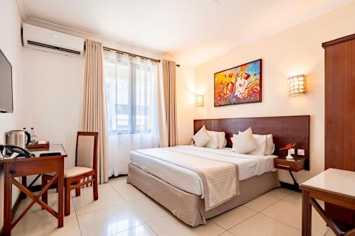 a hotel room with a bed and a desk at PrideInn Hotel Diani in Diani Beach