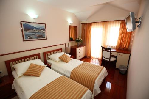 a hotel room with two beds and a desk at Hotel Trogir Palace in Trogir