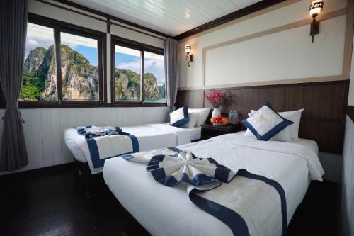 two beds in a room with two windows at Sunlight Legend Cruise in Ha Long