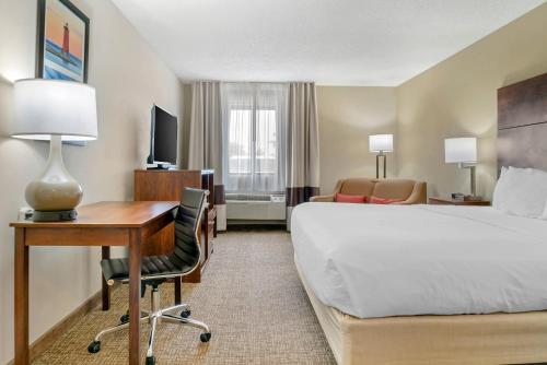 a hotel room with a bed and a desk with a computer at Comfort Inn Manistique in Manistique