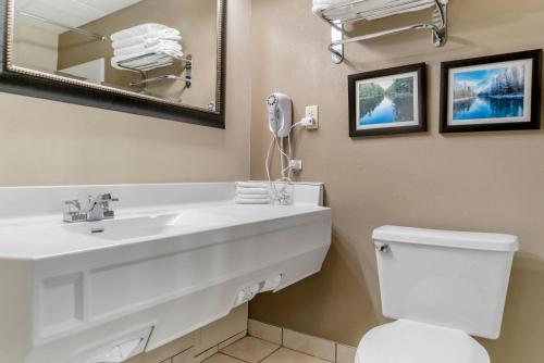 a bathroom with a sink and a toilet and a mirror at Comfort Inn Manistique in Manistique