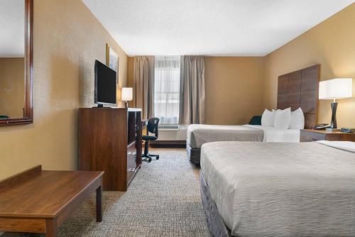 a hotel room with two beds and a flat screen tv at Quality Inn & Suites Manistique in Manistique