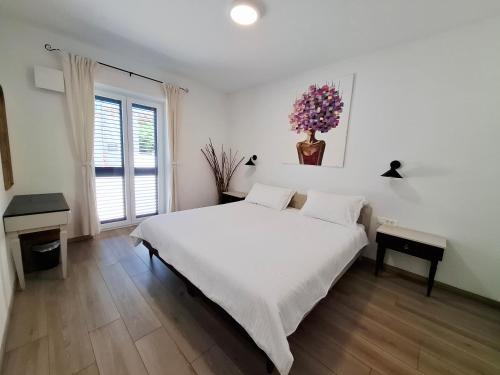 a white bedroom with a bed and a vase of flowers at Apartment MoiRai in Gračišče