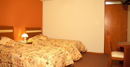 um quarto de hotel com duas camas e uma secretária em Hotel San Andres em Arequipa