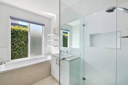 a bathroom with a shower and a sink and a window at Palm Haven Coolum Beach in Coolum Beach