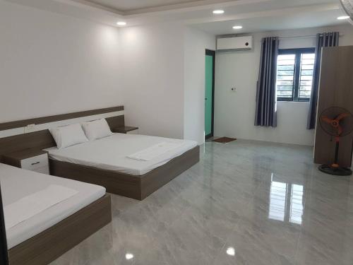 a white room with two beds and a window at Nhà nghỉ My Home in Mộc Châu