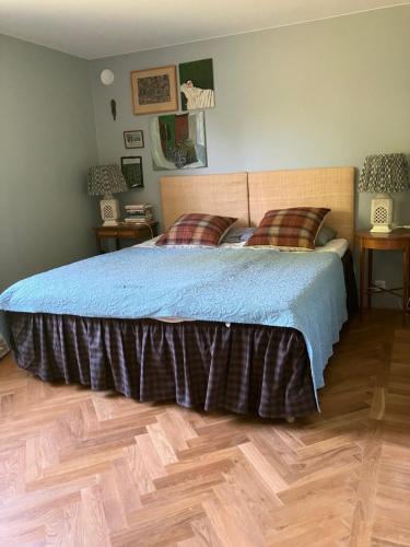 a bedroom with a bed with a blue blanket and wooden floors at Bra familjeboende Vitaby in Vitaby