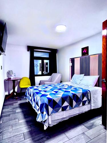 a bedroom with a bed and a chair and a table at Hotel-cafetería TERRAVOLCAN in San Pedro Sacatepéquez