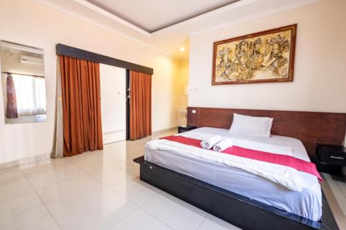 a bedroom with a large bed and a painting on the wall at Samudra Homestay in Kuta