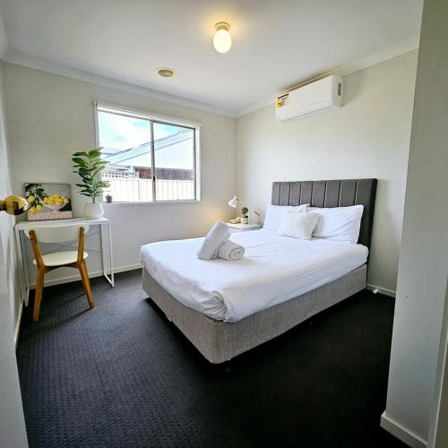 a bedroom with a bed and a desk with a window at Comfort on Mozart in Shepparton